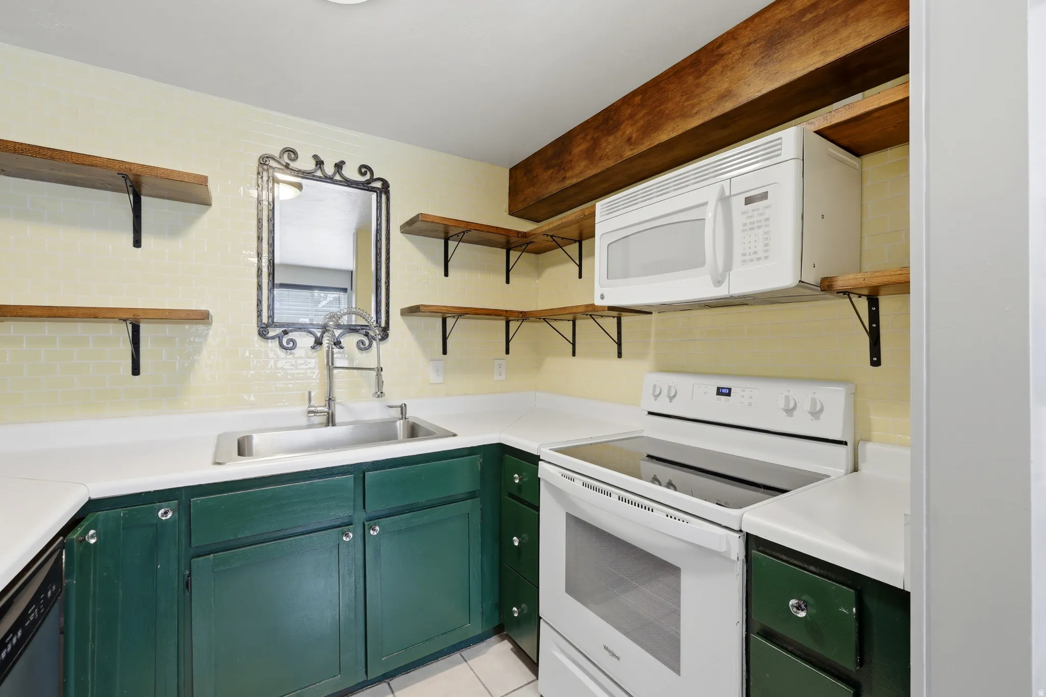 Kitchen featuring white countertops, green base cabinetry, and a light-colored subway tile backsplash