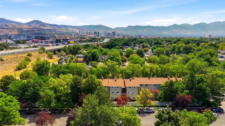 Residential buildings set amongst mature trees, with a distant city skyline and mountain backdrop