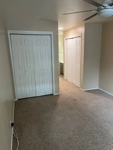 Carpet flooring, multiple bi-fold closet doors, ceiling-mounted light fixture, recessed lighting, and neutral wall tones
