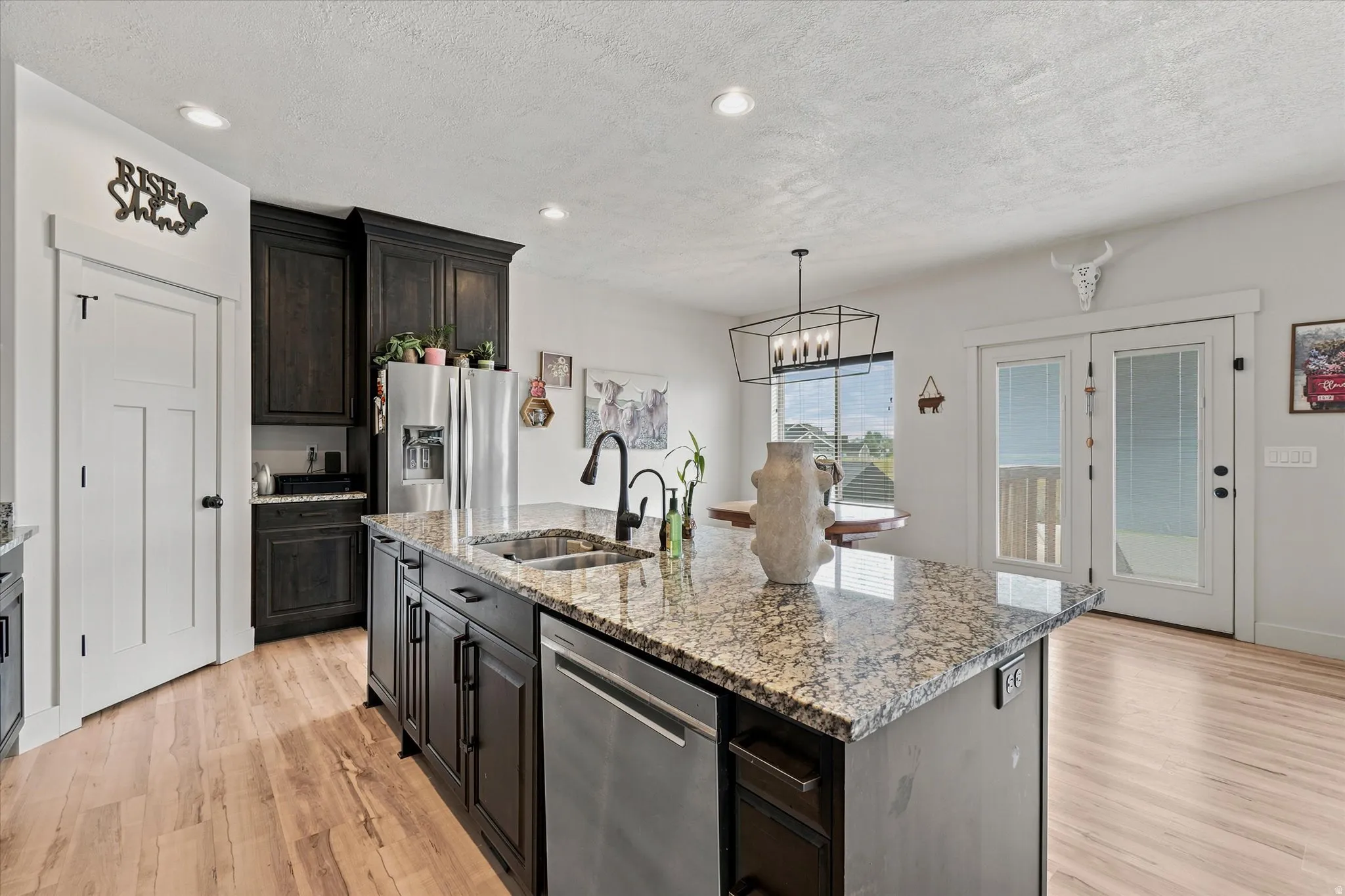 Kitchen island featuring a granite countertop, undermount stainless steel sink, and dishwasher