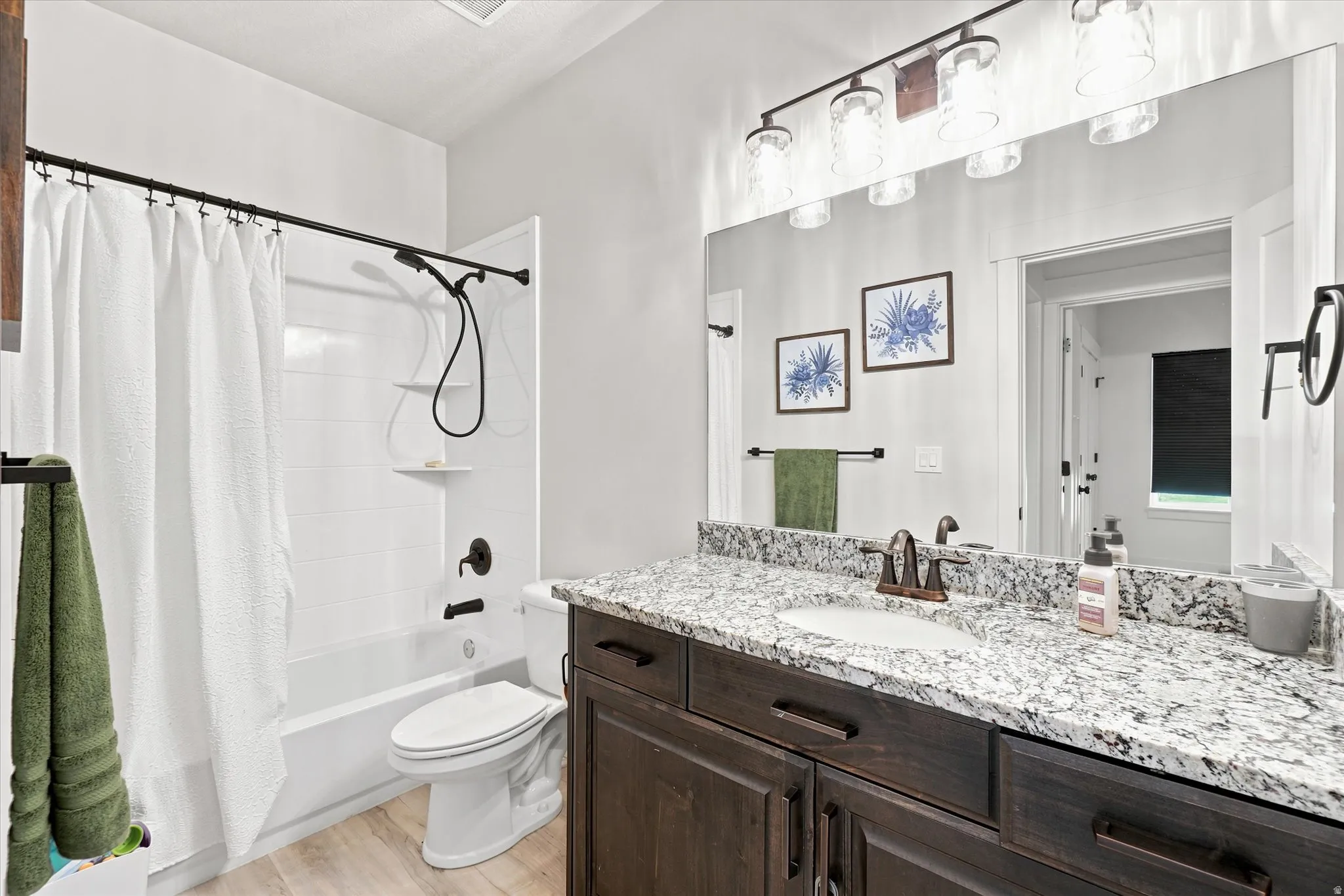 Bathroom featuring a dark wood-finish vanity with a speckled countertop, undermount sink, and a large wall-mounted mirror