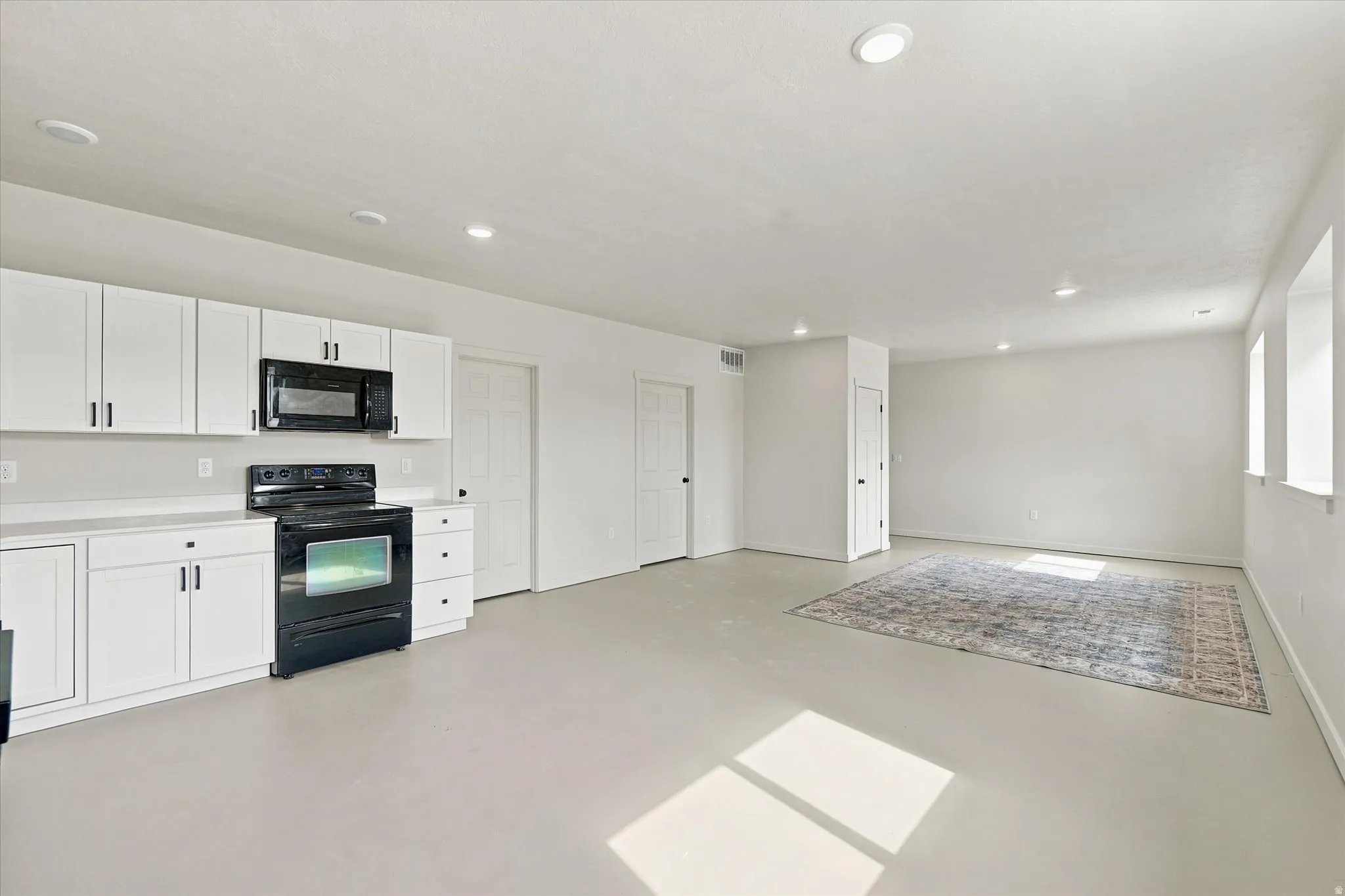 Open-concept living space with light-toned flooring and recessed ceiling lights
