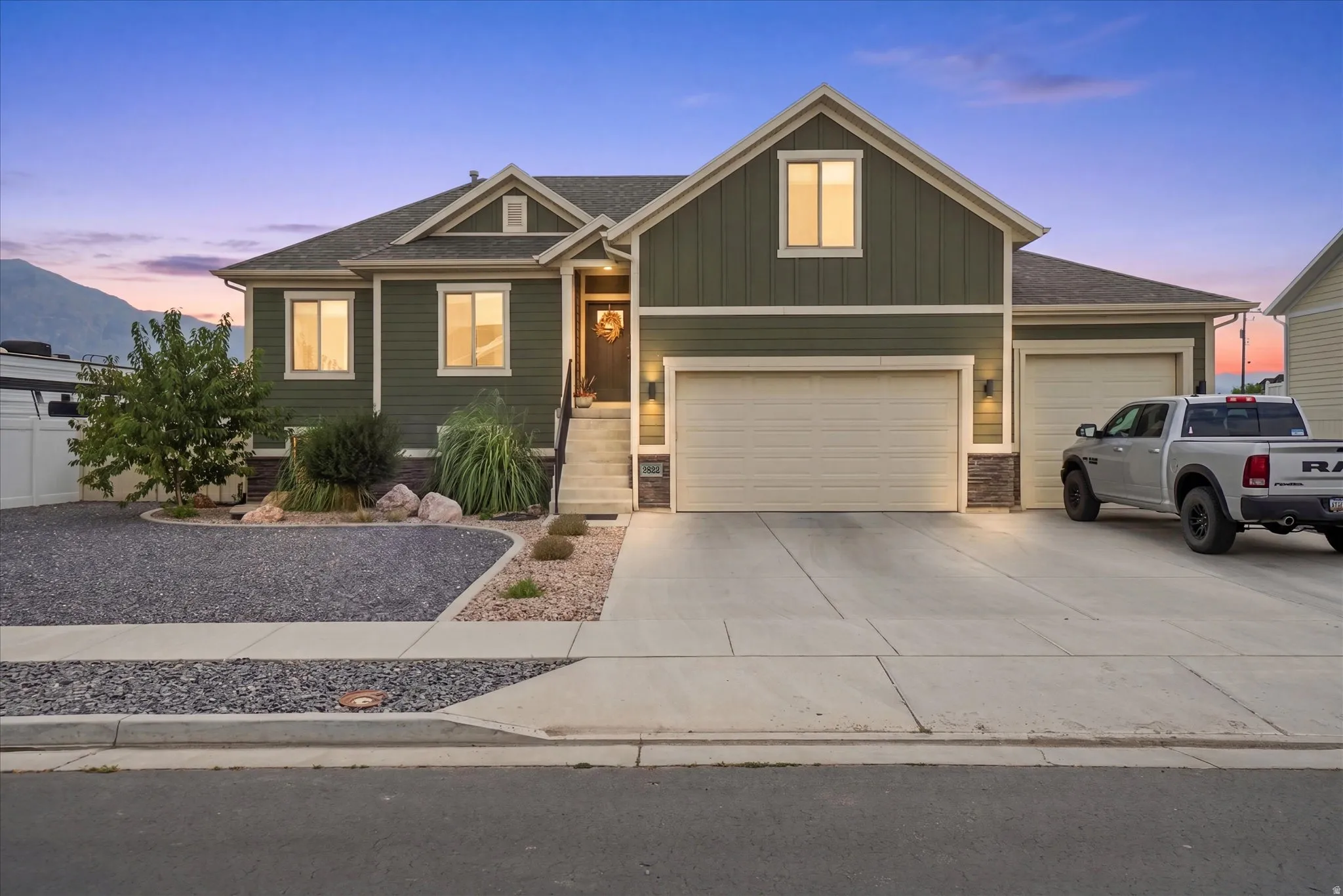 Contemporary home featuring an olive green exterior, stone accents, and a large multi-car garage with concrete driveway