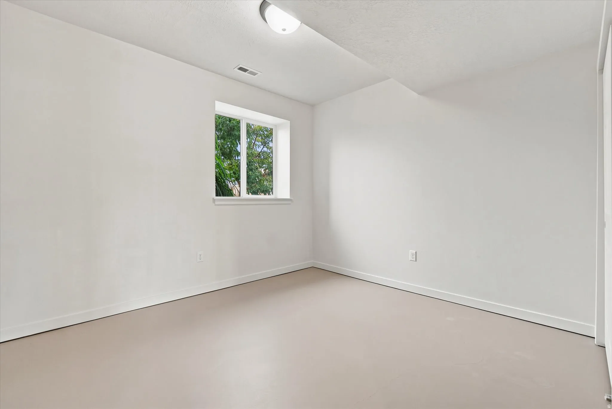 Room featuring an egress window, light-toned flooring, white walls, and a flush-mount ceiling light