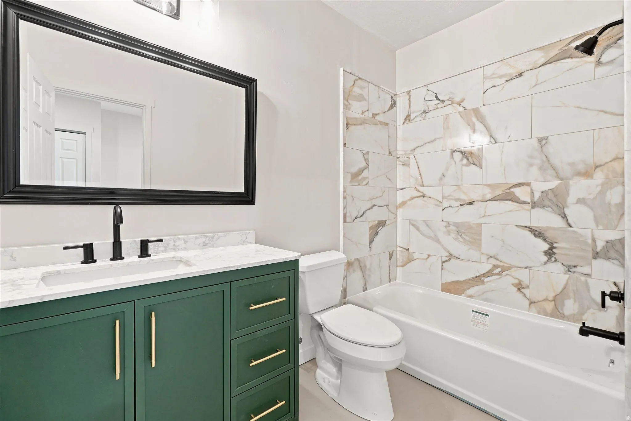 Bathroom featuring a green vanity with gold hardware, white countertop with integrated sink, and matte black fixtures
