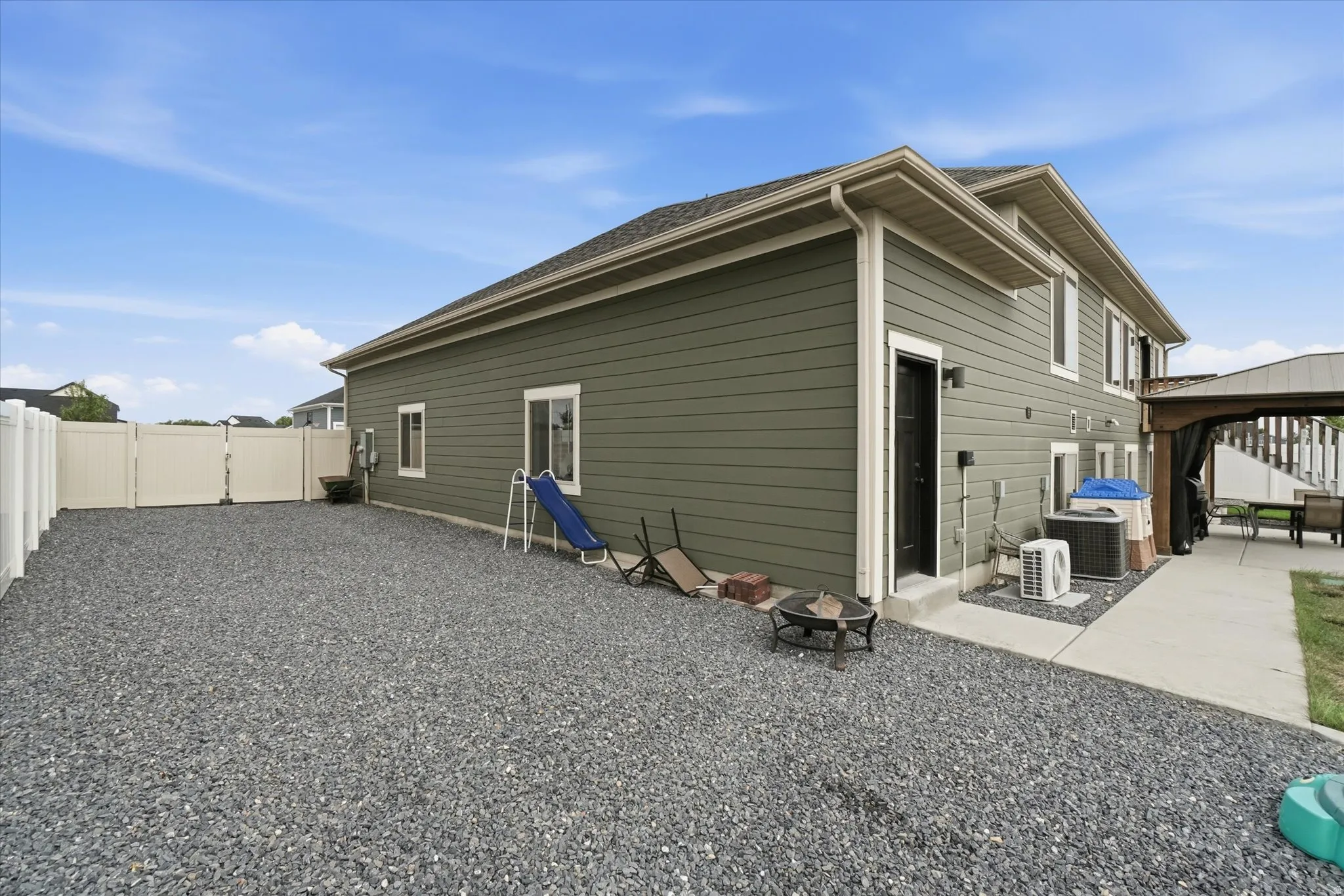 Exterior featuring olive green siding, white trim, and a gravel yard