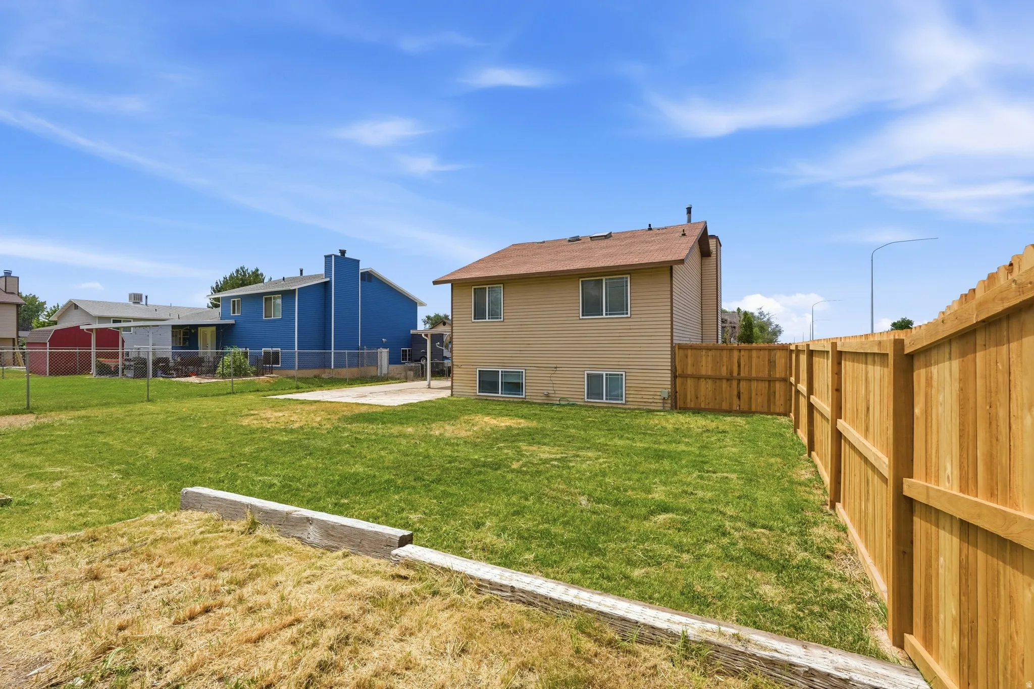 Expansive backyard featuring a new wood privacy fence, green lawn, and concrete patio