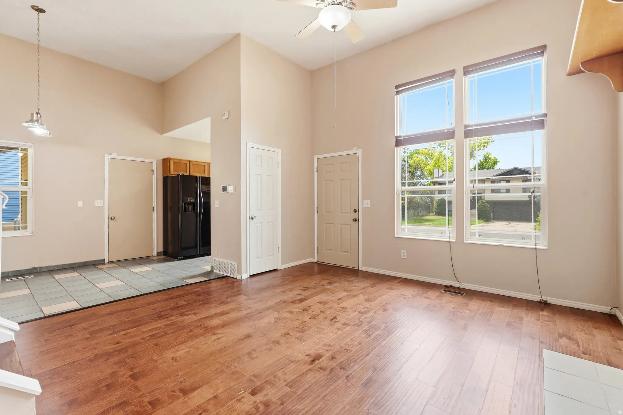 Vaulted ceilings enhance this open-concept room featuring wood-finish flooring and a ceiling fan with integrated lighting
