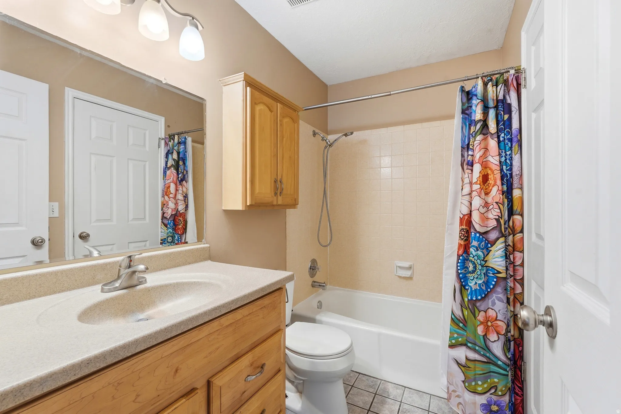 Bathroom featuring a wood-finish vanity with an integrated sink and light-colored countertop