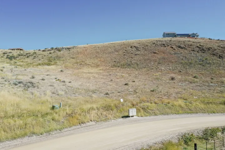 Expansive undeveloped land parcel featuring a dirt road frontage and utility access points