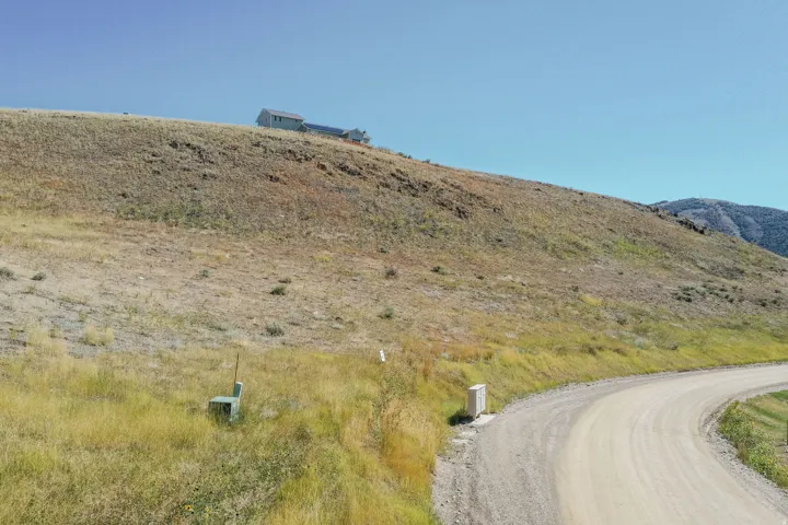 Gravel road winding through a sloped, arid landscape with a distant structure visible on the horizon