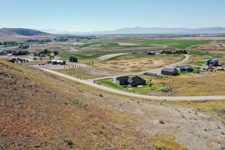 Expansive rural landscape featuring a winding road and distant residential properties