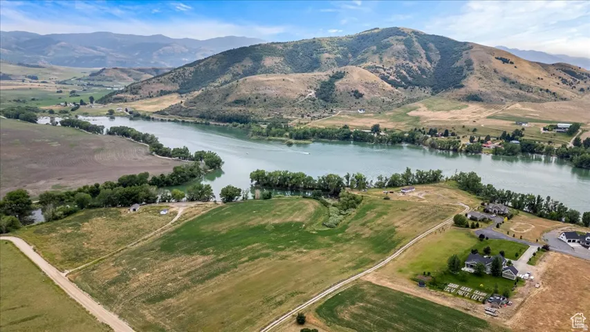 Expansive waterfront property featuring a wide river, surrounding mountains, open fields, and residential properties