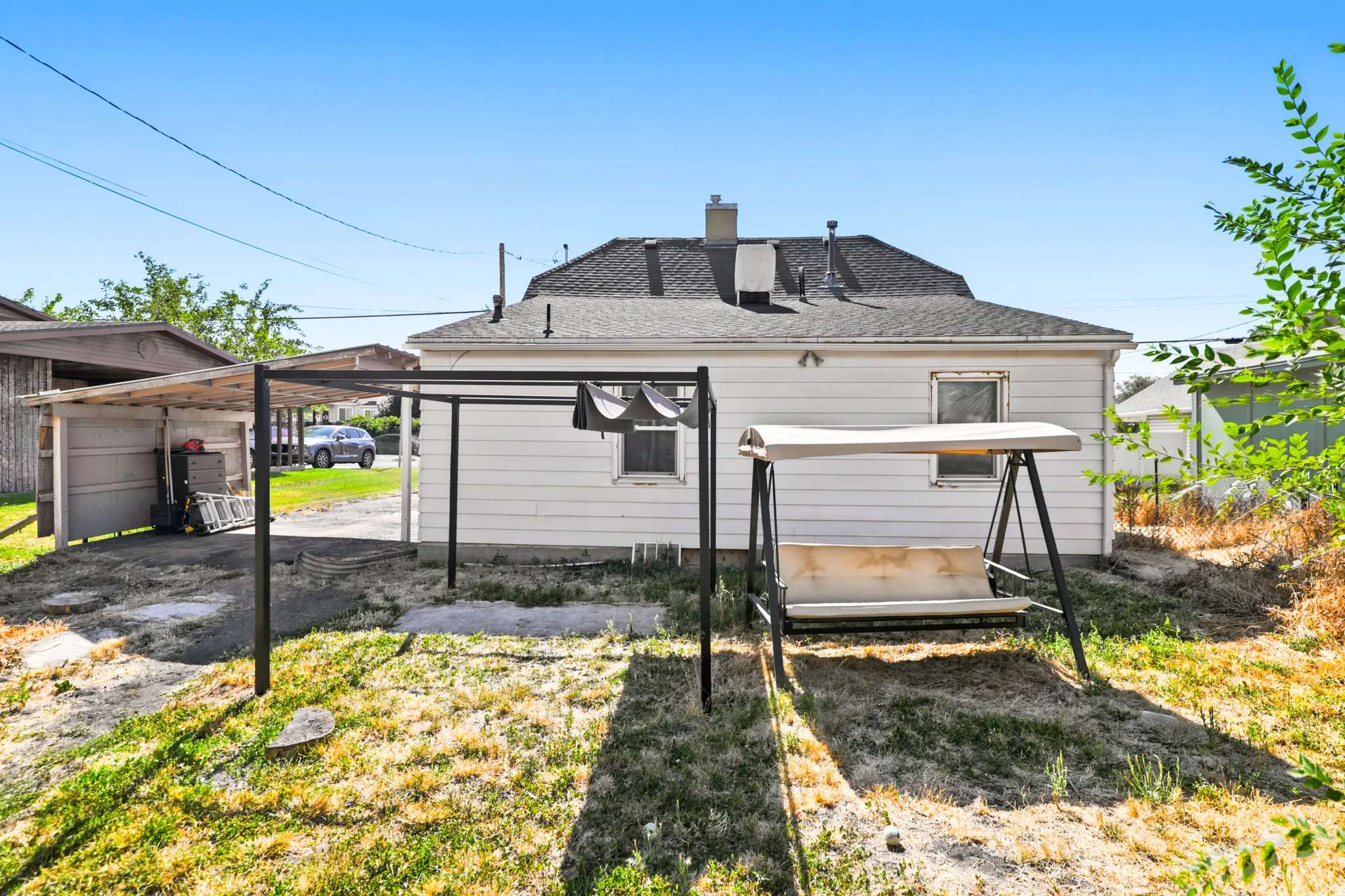 Rear exterior featuring white siding and a dark shingle roof