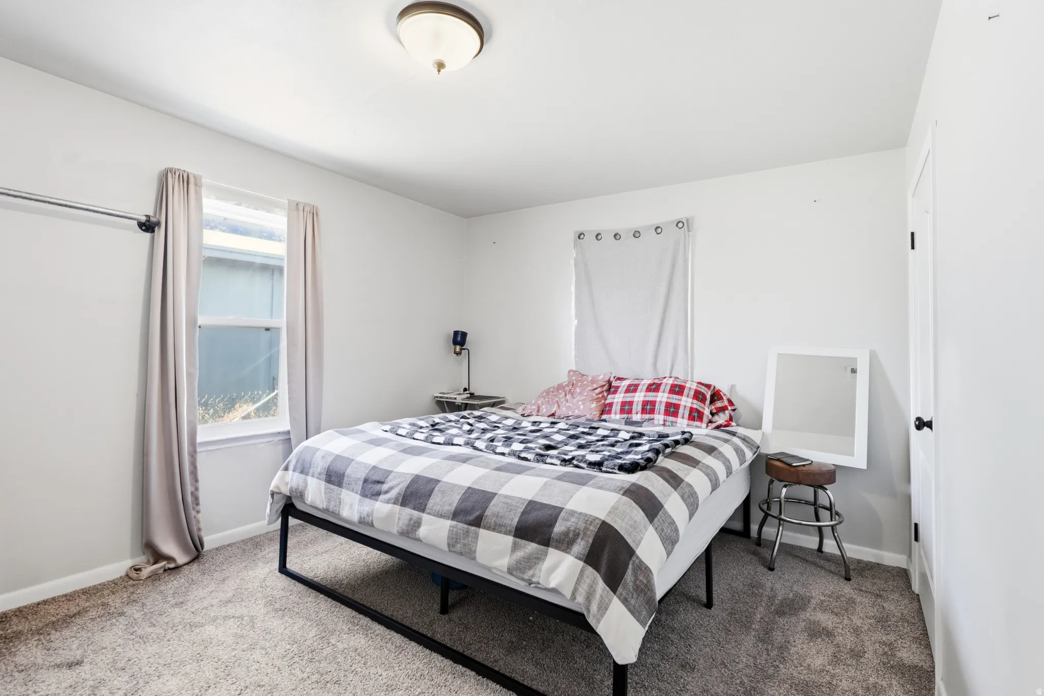 Neutral-toned bedroom featuring wall-to-wall carpeting and a ceiling-mounted light fixture