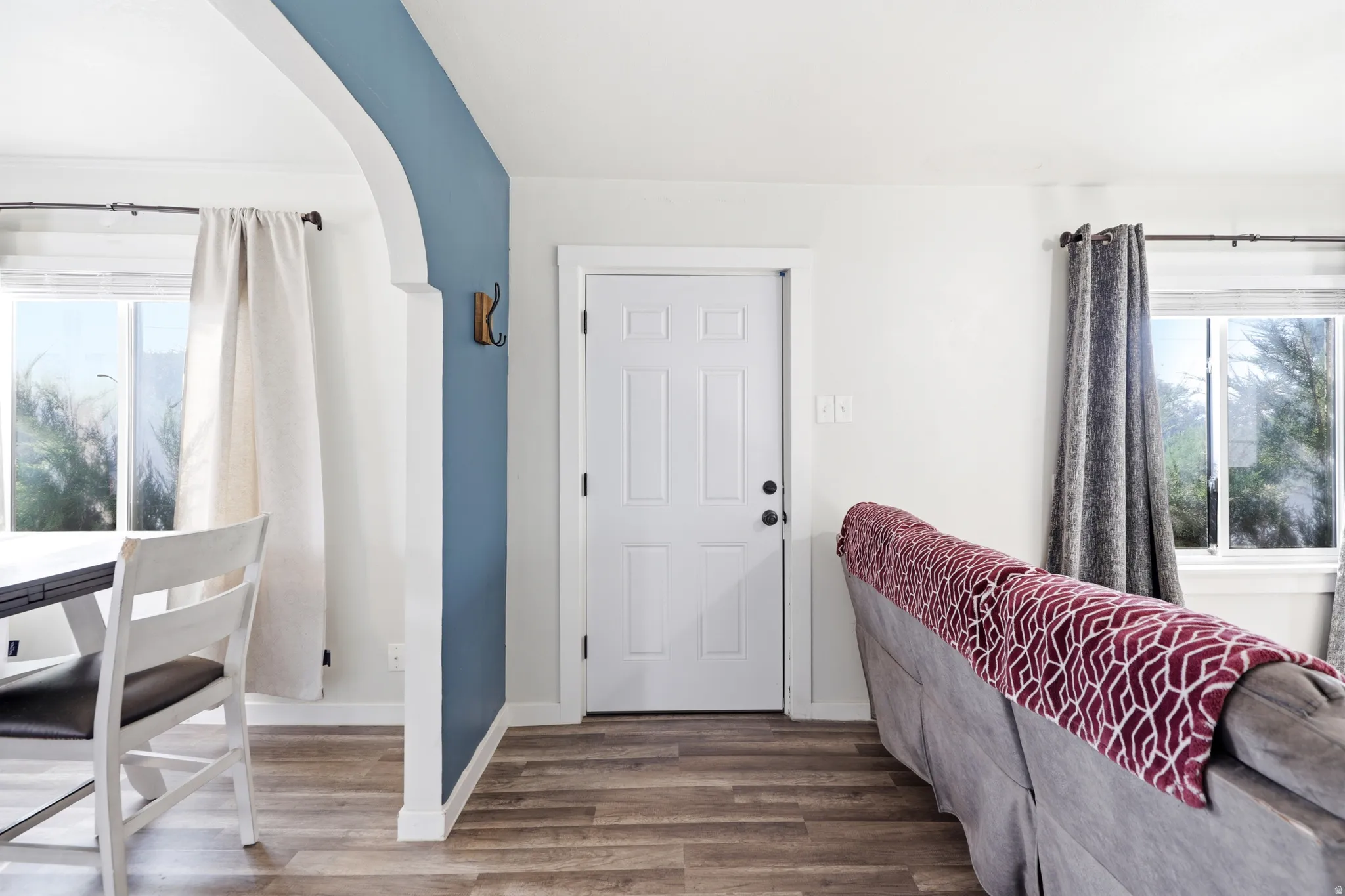 Entryway featuring a paneled door, wood-finish flooring, and crisp white walls with an accent color