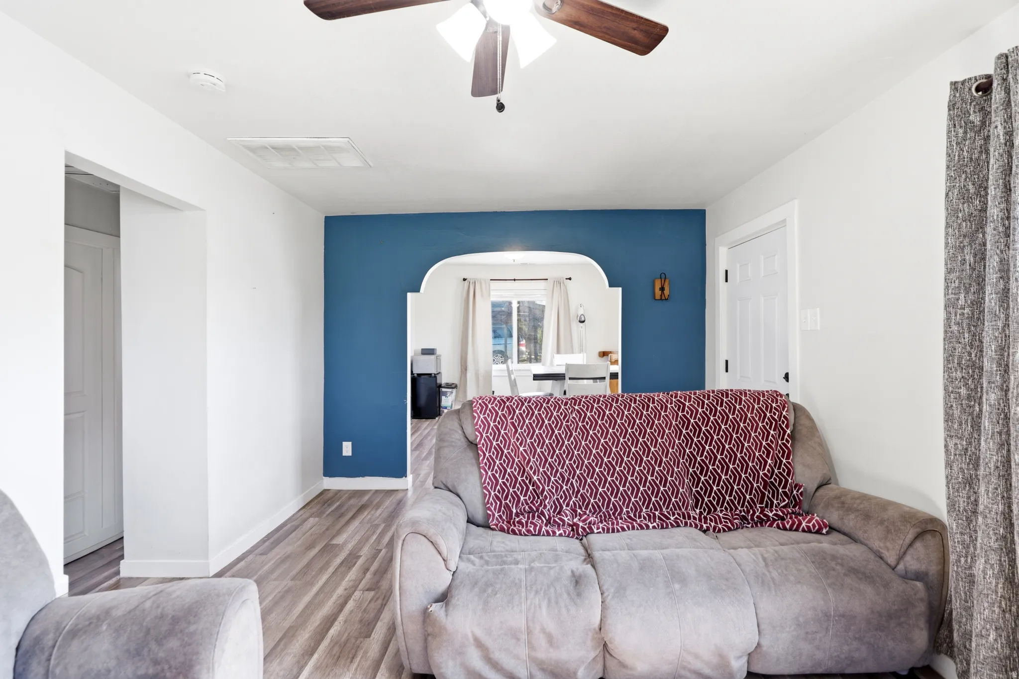Living space featuring wood-finish flooring and a ceiling fan with integrated lighting