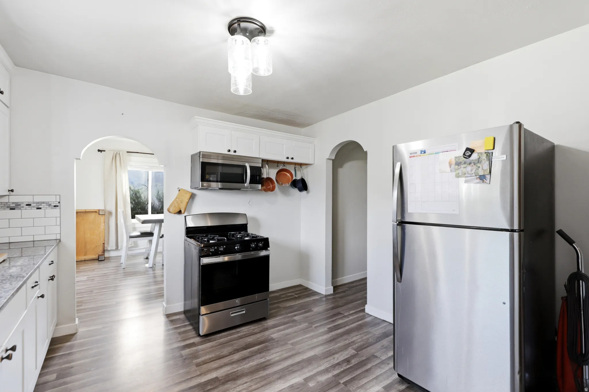 Kitchen featuring wood-finish flooring, white cabinetry, a stainless steel range, and an over-the-range microwave