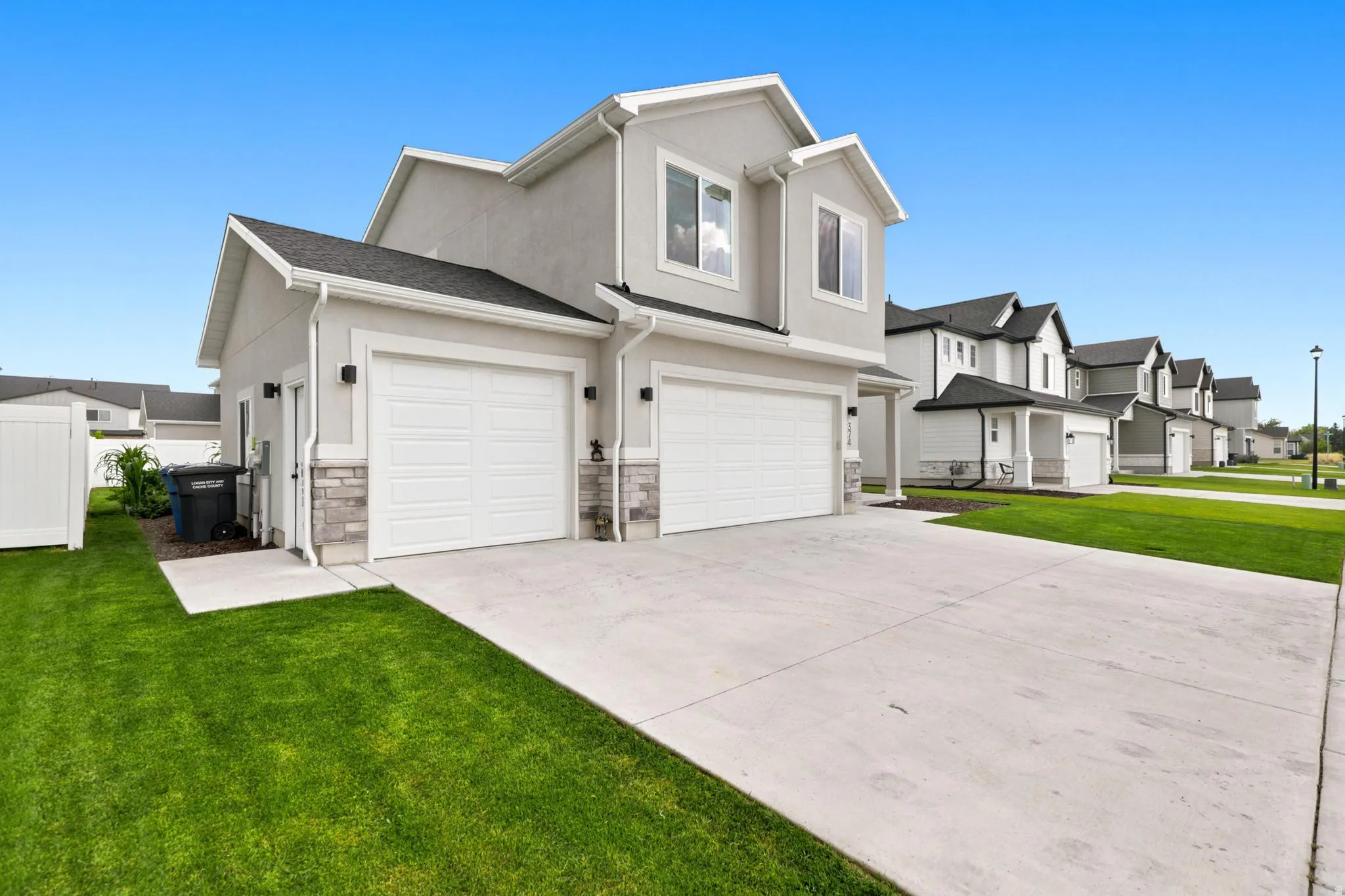 Contemporary two-story residence with a stucco exterior, stone accents, and a two-car garage