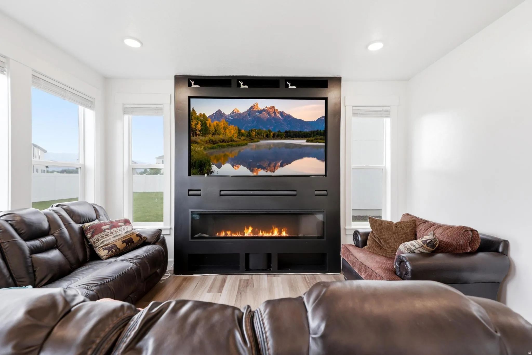 Integrated entertainment wall with a linear electric fireplace, recessed television, and built-in shelving