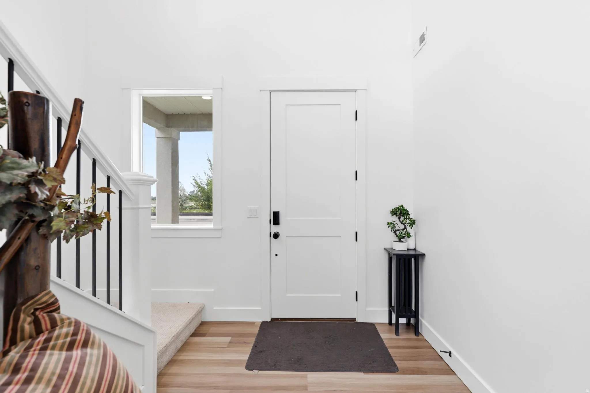 Entryway featuring a solid panel door, wood-finish flooring, and white baseboards