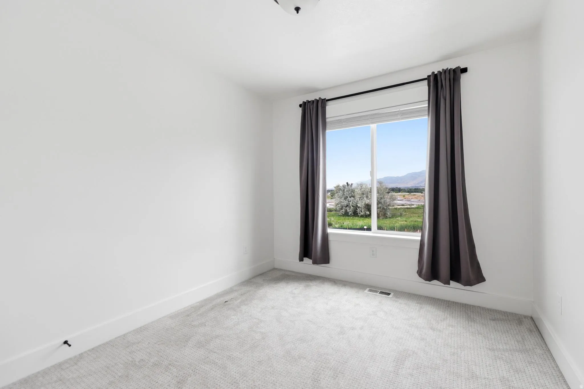 Bright room featuring white walls, gray patterned carpeting, a large window, and white trim