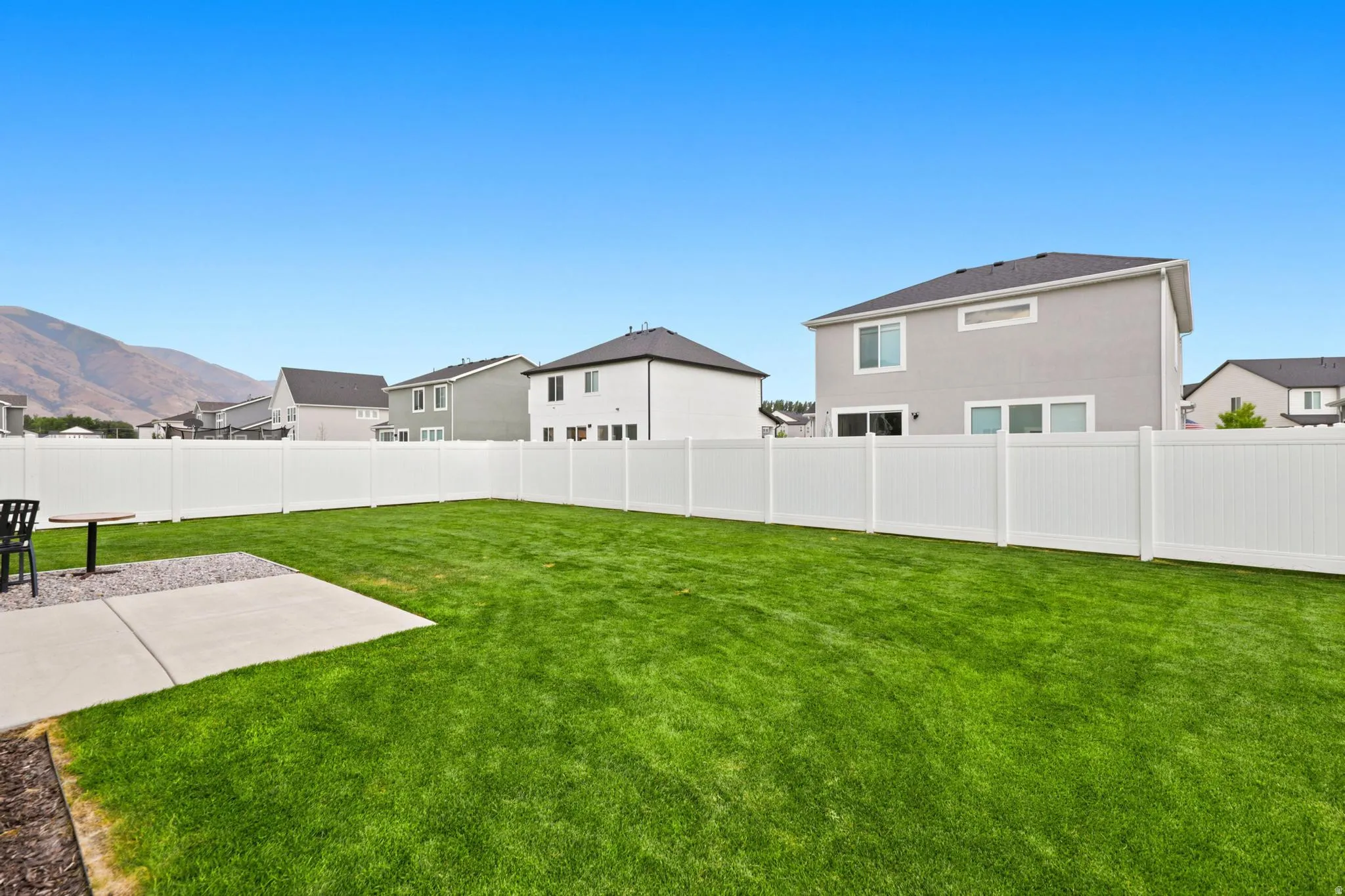 Expansive green lawn with a white privacy fence