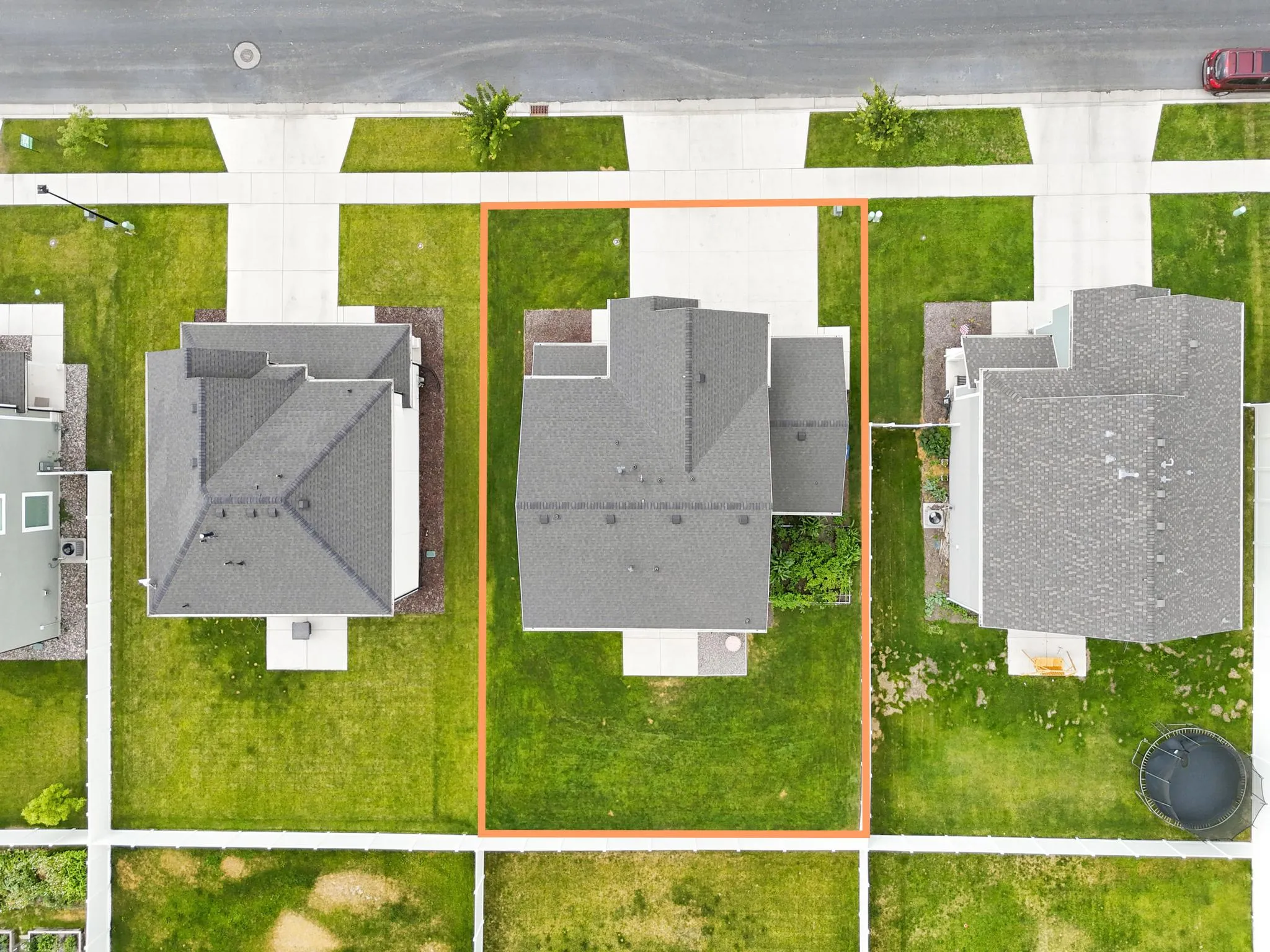 Aerial view of a residential property featuring a large green lawn surrounding a grey-roofed home