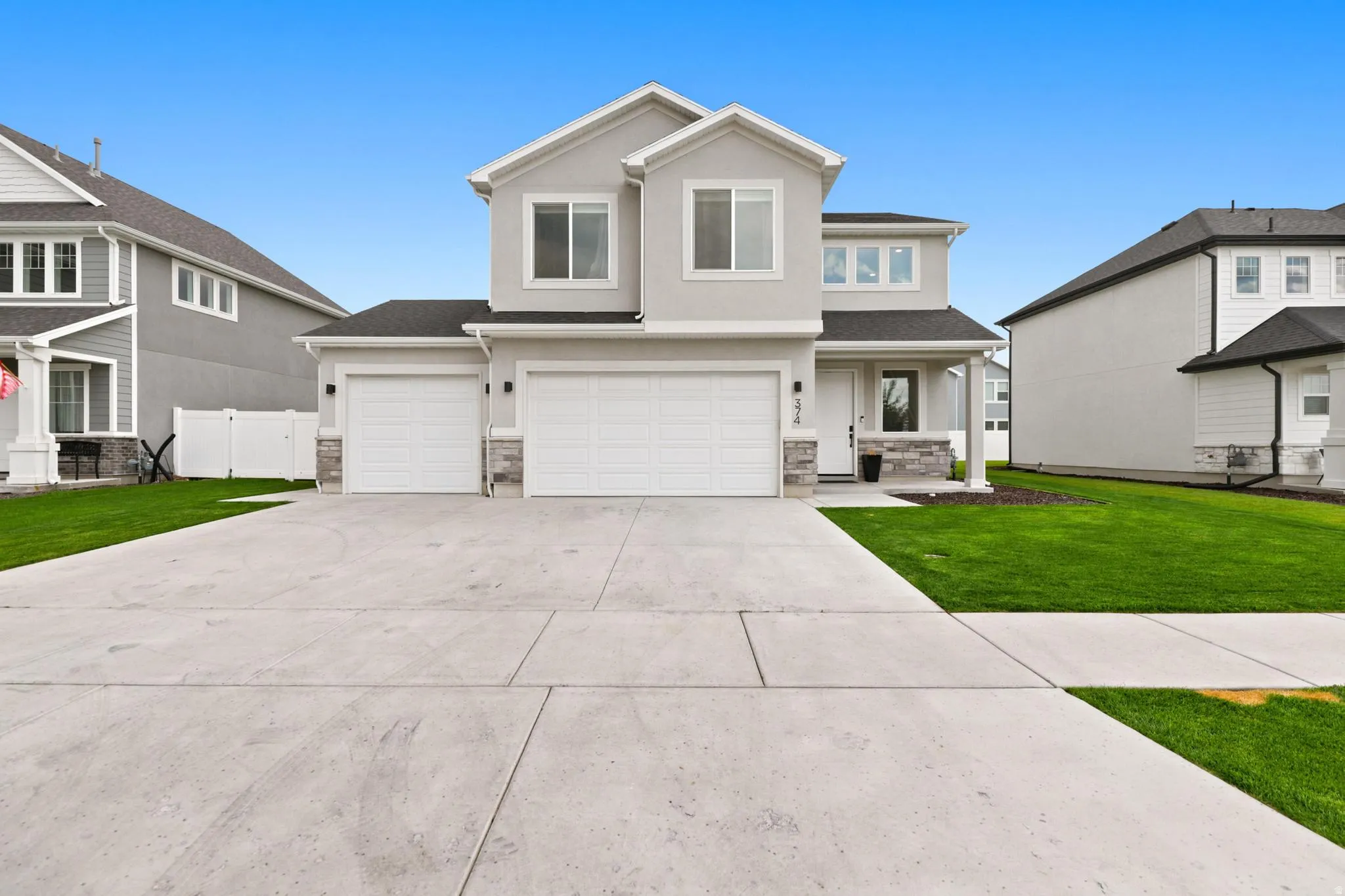 Contemporary two-story residence featuring a light gray exterior, dark shingle roof, and a two-car garage with white doors