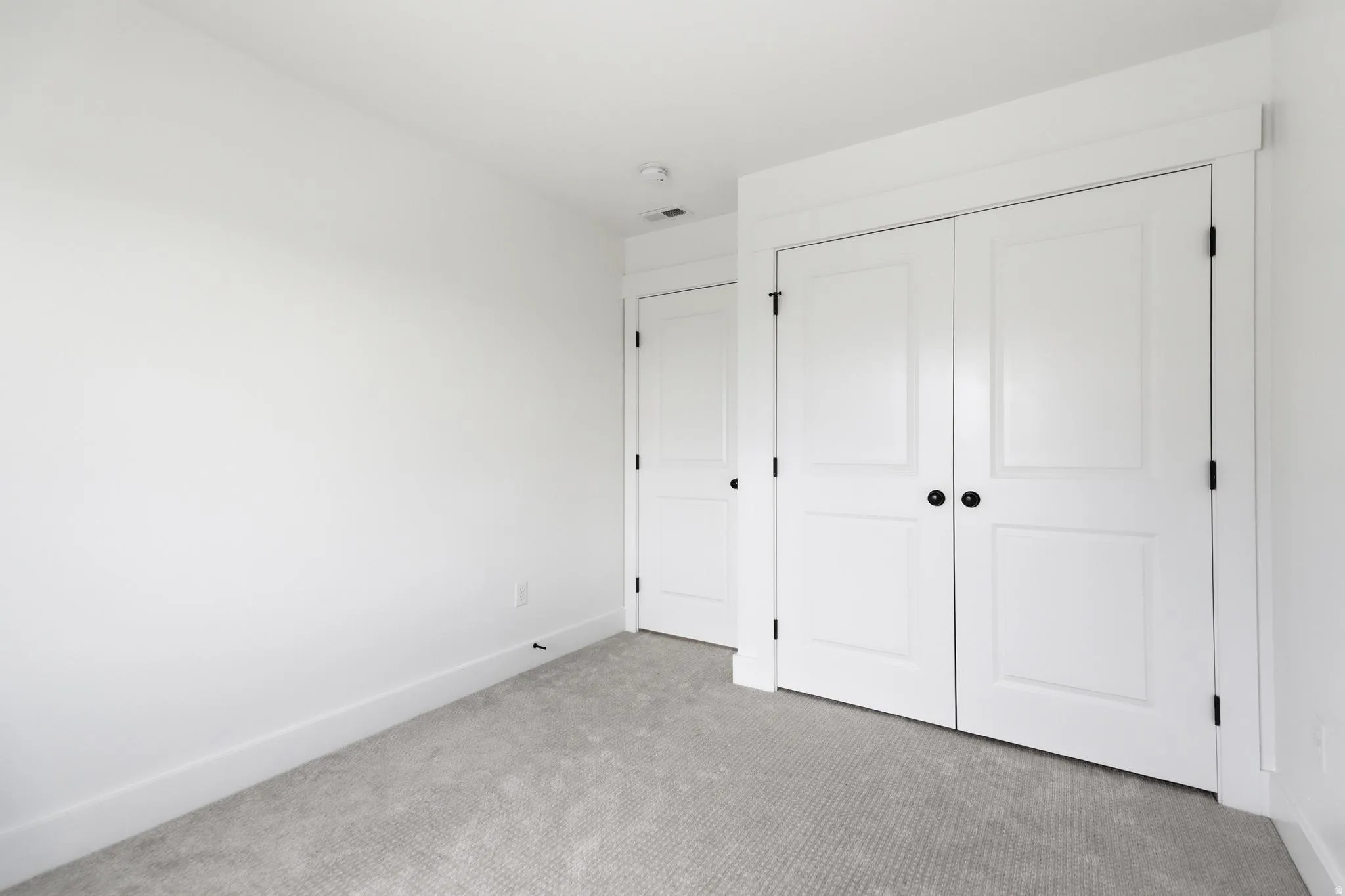 Room featuring neutral gray carpet, white painted walls, white baseboards, and a white ceiling