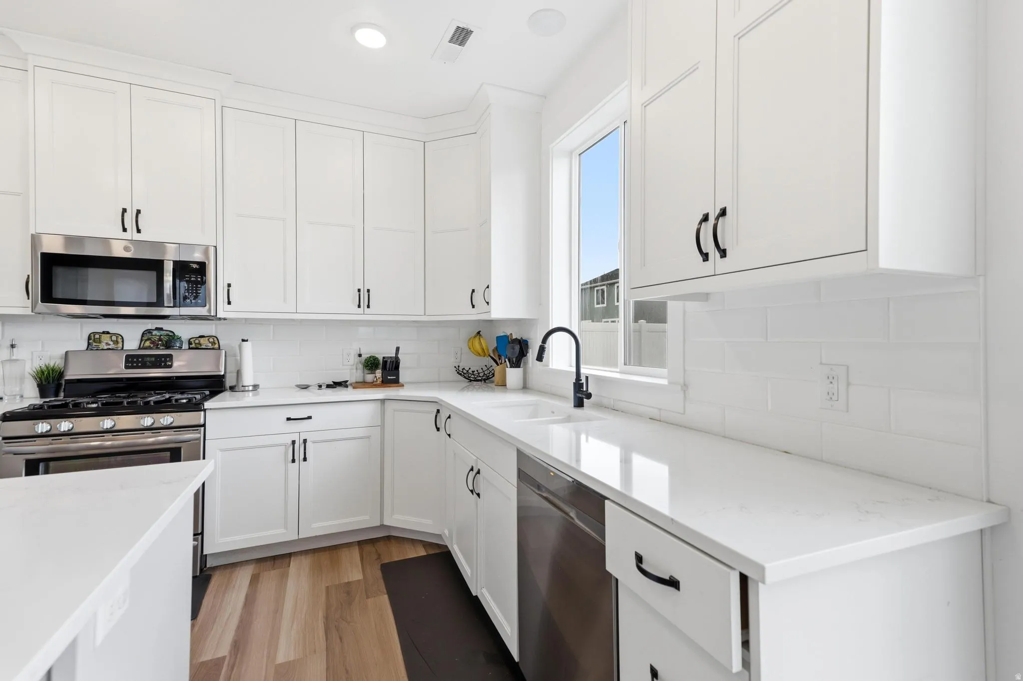 White shaker cabinetry paired with light-toned countertops and a matching subway tile backsplash