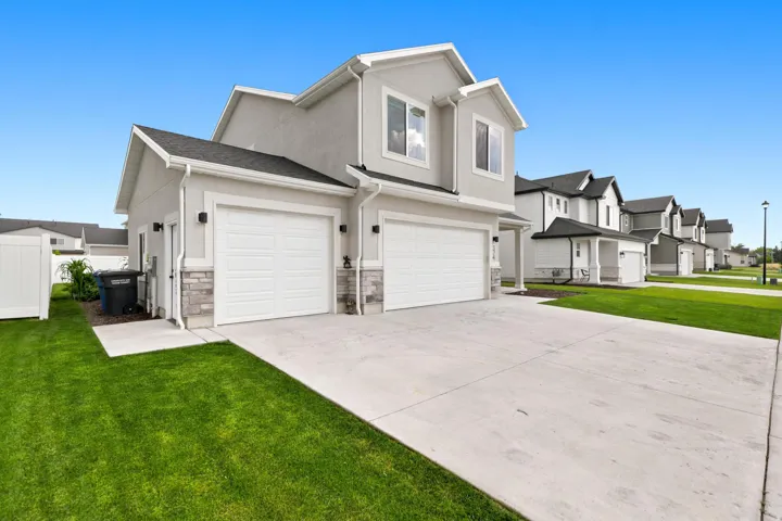 Contemporary two-story residence with a stucco exterior, stone accents, and a two-car garage