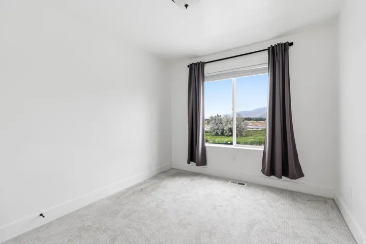Bright room featuring white walls, gray patterned carpeting, a large window, and white trim