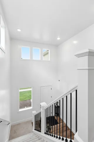 Two-story foyer featuring a contemporary staircase with black wrought iron spindles and white newel posts, high ceilings, recessed lighting, and multiple windows