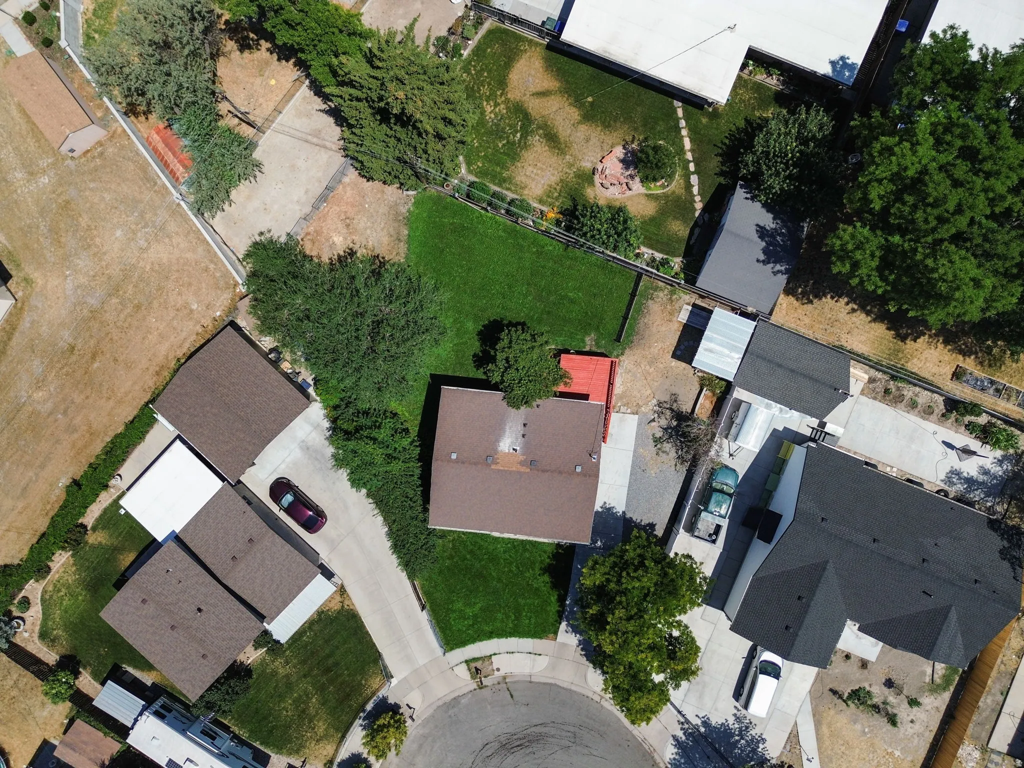 Property with a cul-de-sac location, featuring a brown shingle roof, a paved driveway, and established perimeter trees