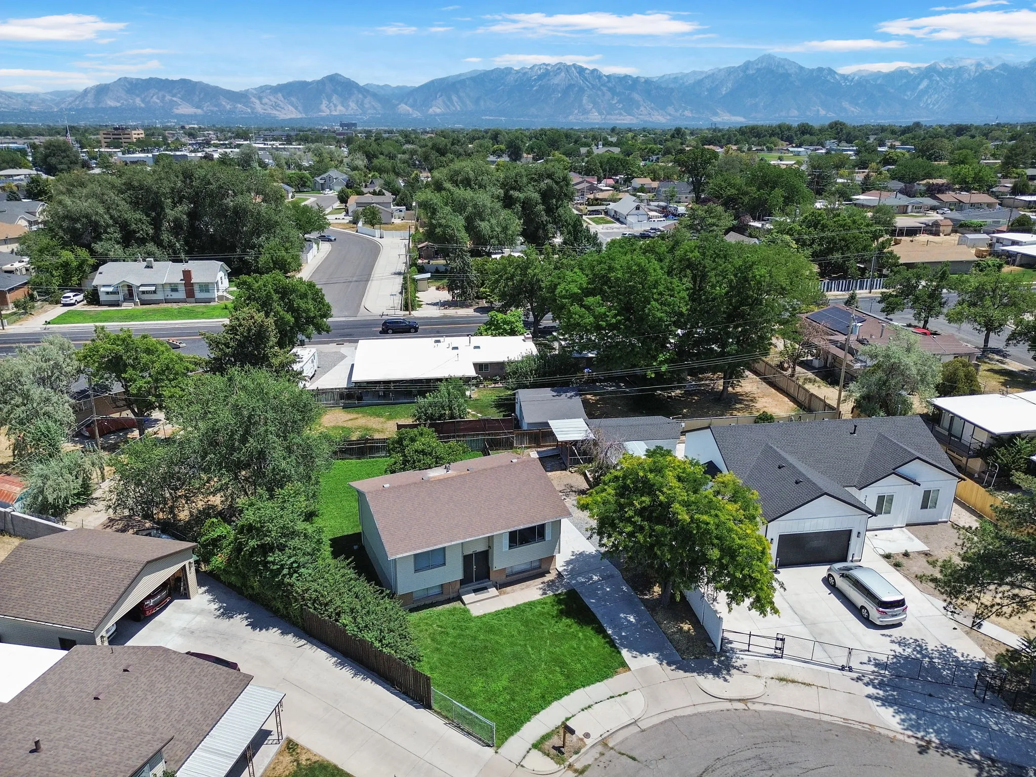 Residential property featuring a manicured lawn, established trees, and a mountain backdrop