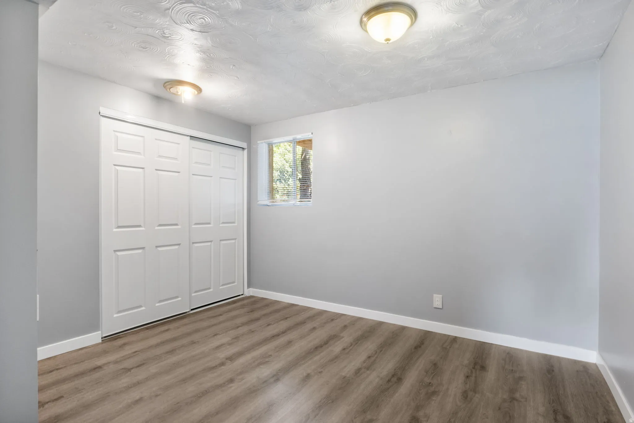 Room featuring wood-finish flooring, light gray walls, and white trim