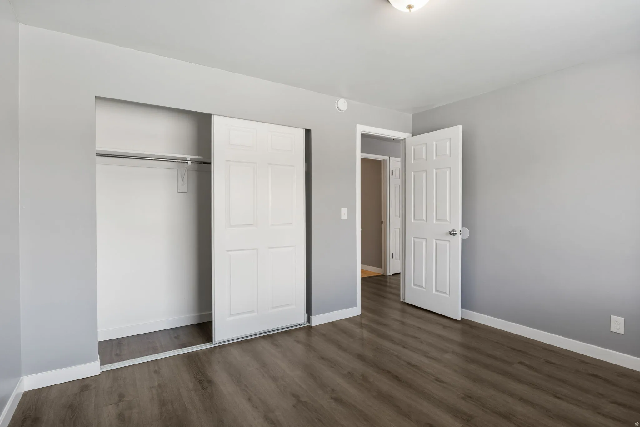 Bedroom featuring wood-finish flooring, light gray wall paint, and white baseboards