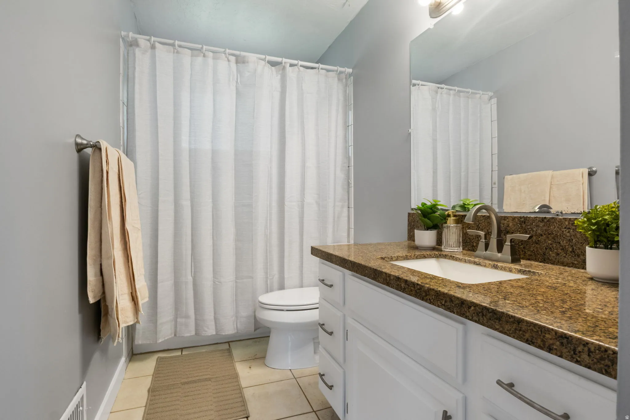 Bathroom vanity with a brown speckled countertop, an undermount sink, and brushed nickel hardware