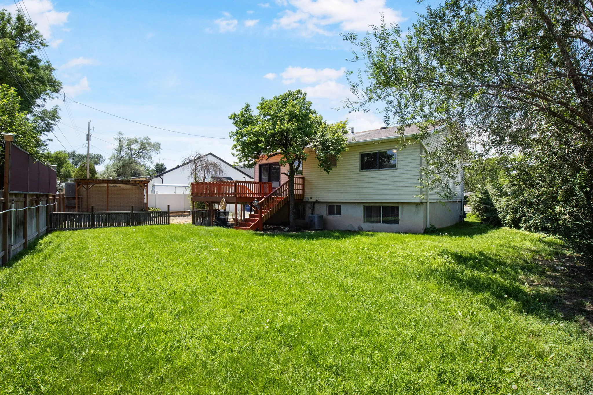 Expansive rear yard featuring a large grass area, a two-story wood deck, and a fenced perimeter