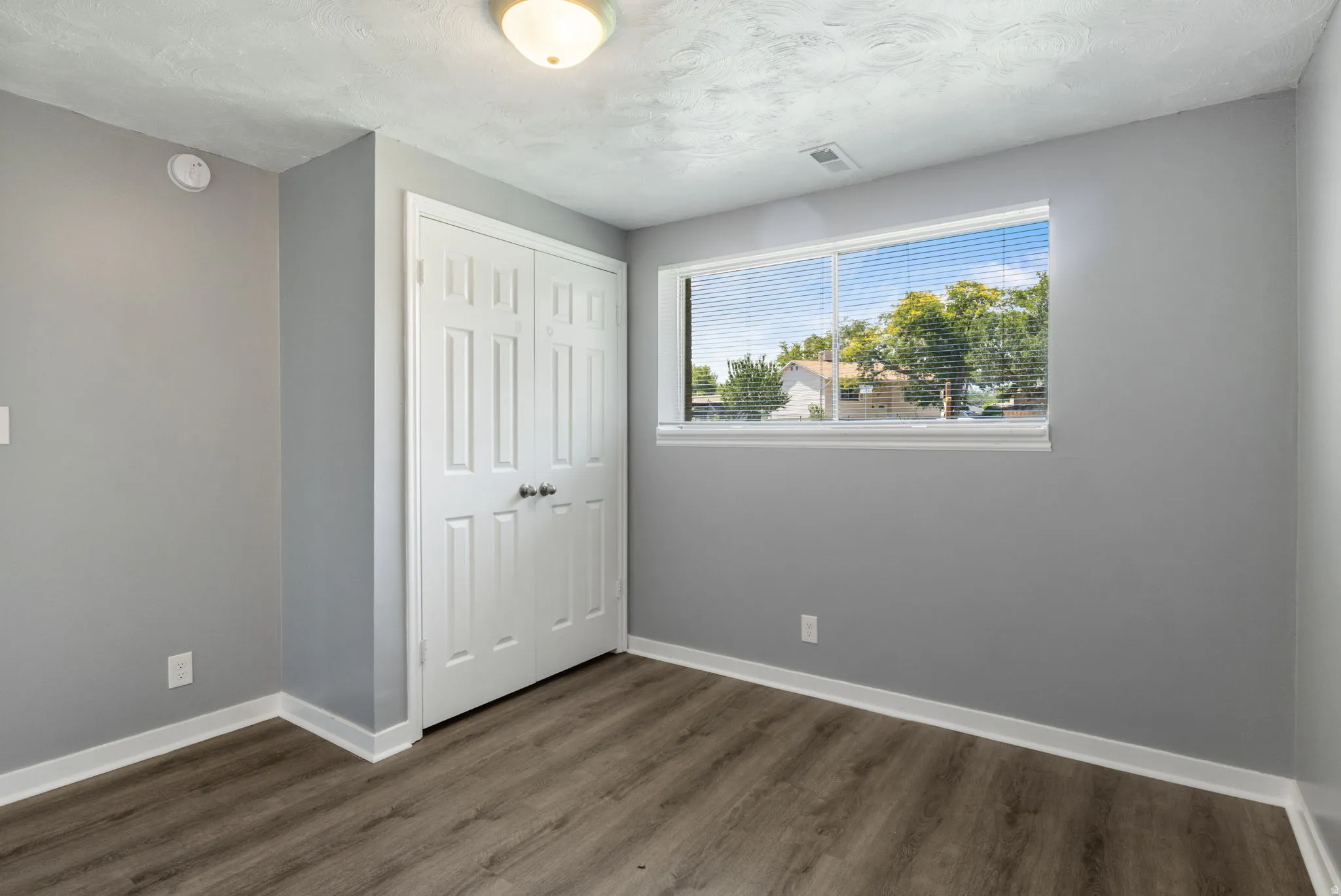 Room featuring wood-finish flooring, light grey walls, and white trim