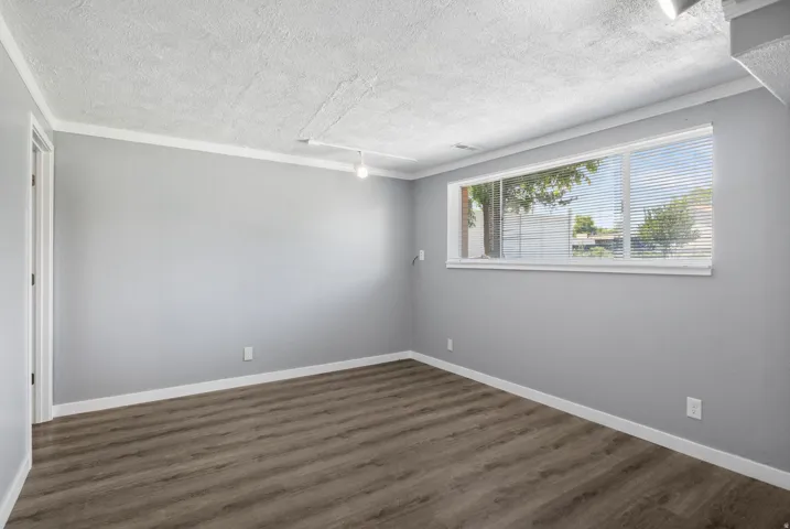 Room featuring wood-finish flooring, light gray wall paint, and white baseboards