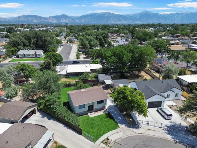 Residential property featuring a manicured lawn, established trees, and a mountain backdrop