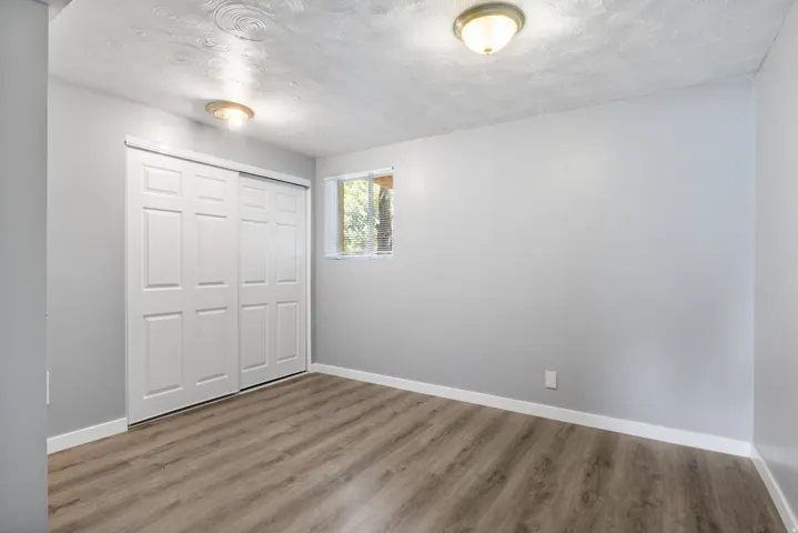 Room featuring wood-finish flooring, light gray walls, and white trim