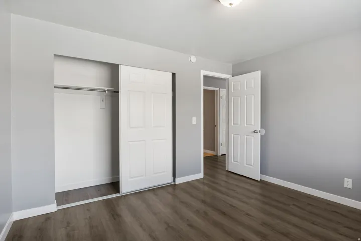Bedroom featuring wood-finish flooring, light gray wall paint, and white baseboards