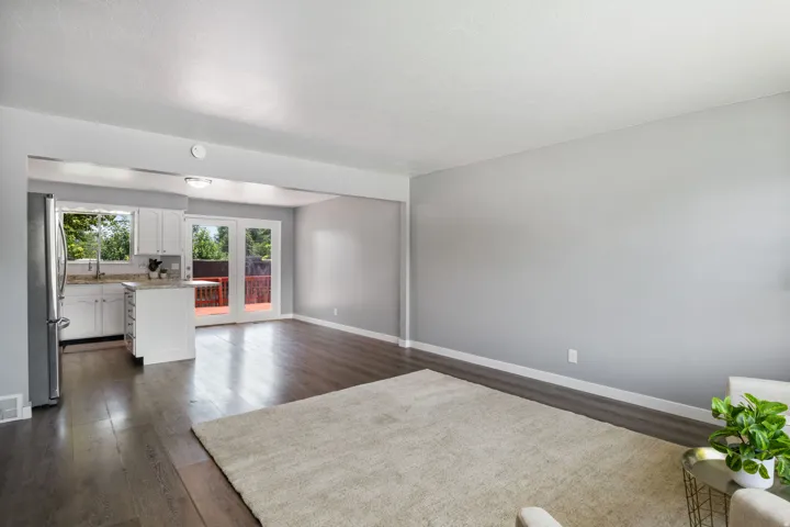 Open-concept living area featuring wood-finish flooring, light gray walls, and a recessed kitchen