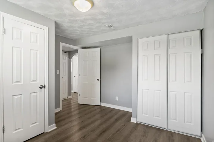 Spacious interior room featuring wood-finish flooring, light gray walls, and white trim