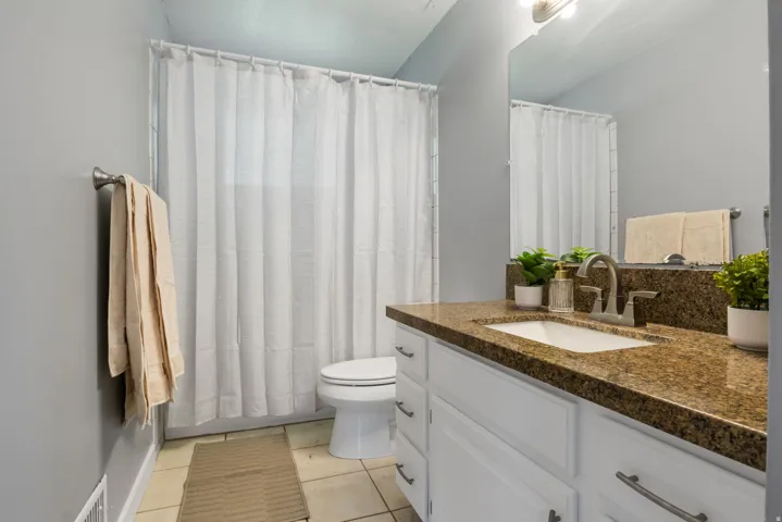 Bathroom vanity with a brown speckled countertop, an undermount sink, and brushed nickel hardware