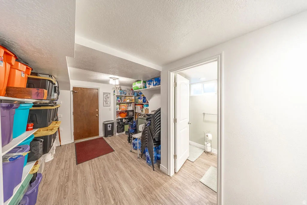 Wood-finish flooring throughout the space, featuring shelves for storage, access to the garage, bathroom, bedrooms, and laundry.