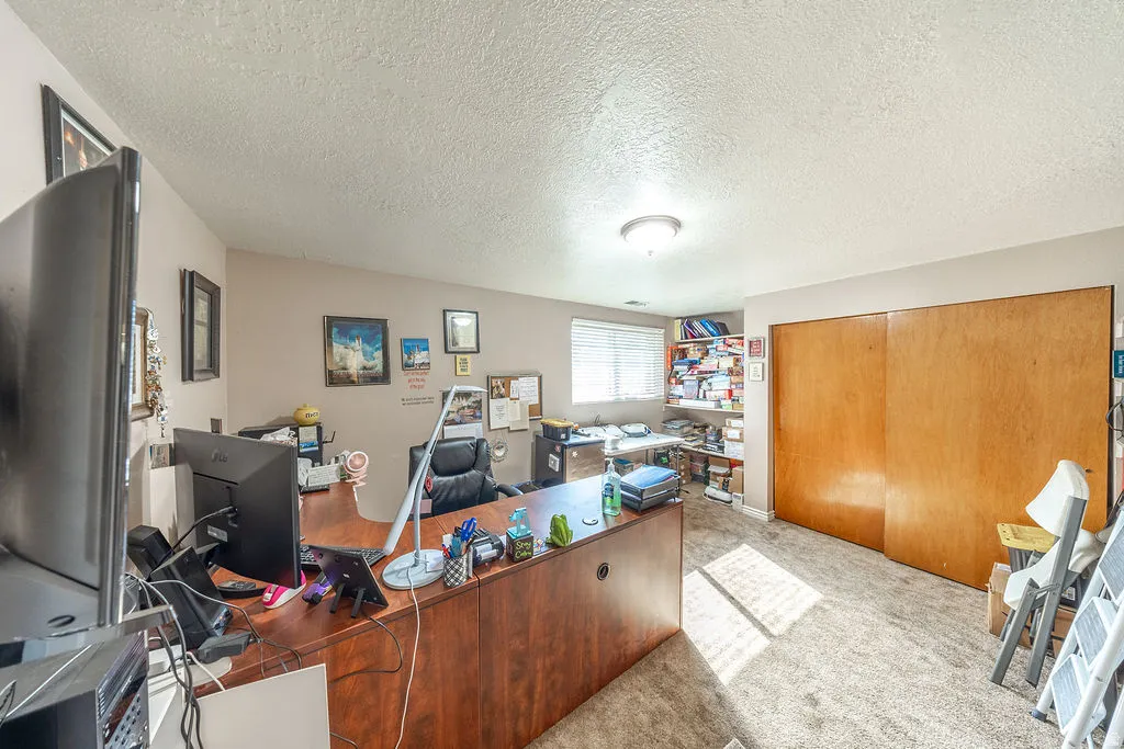 Flexible room featuring carpet flooring, natural light from a window with blinds, and a built-in closet with sliding wood doors and so many shelves for books.  Currently used as an office.